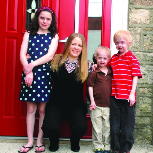 Amy Ruhf (crouching) poses with (from left) Libby, Bennett and Nathan Falcone. Nathan and Bennett suffer from progeria, a rare disorder that causes children to age prematurely and have shortened lifespans.  